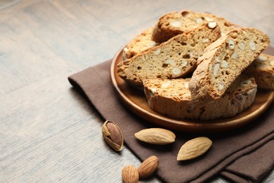 Photo of Traditional Italian almond biscuits (Cantucci) and nuts on wooden table, closeup. Space for text