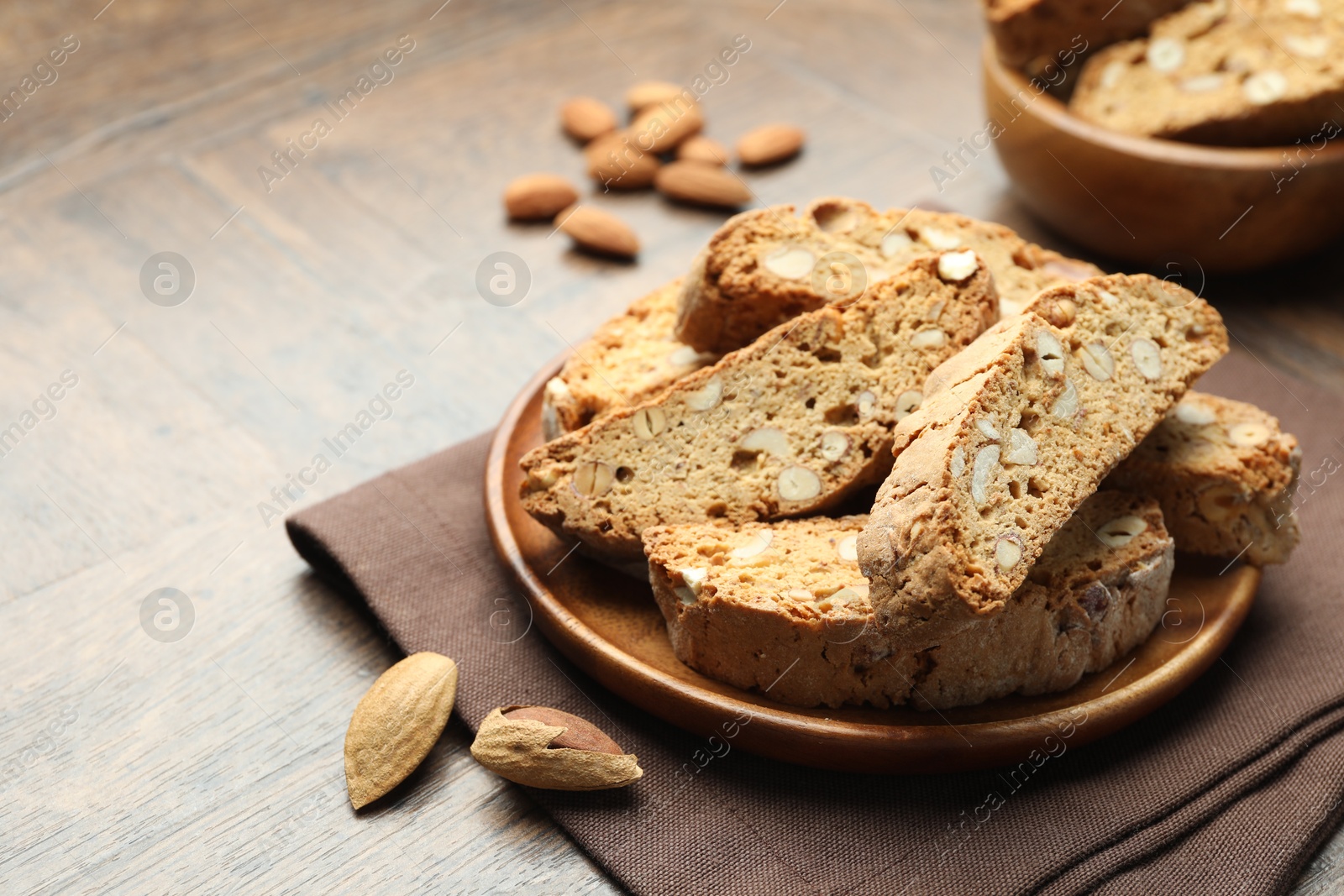 Photo of Traditional Italian almond biscuits (Cantucci) and nuts on wooden table, closeup. Space for text