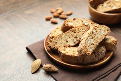 Photo of Traditional Italian almond biscuits (Cantucci) and nuts on wooden table, closeup. Space for text