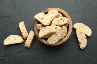 Photo of Traditional Italian almond biscuits (Cantucci) in bowl on black table, top view