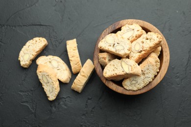 Photo of Traditional Italian almond biscuits (Cantucci) in bowl on black table, top view