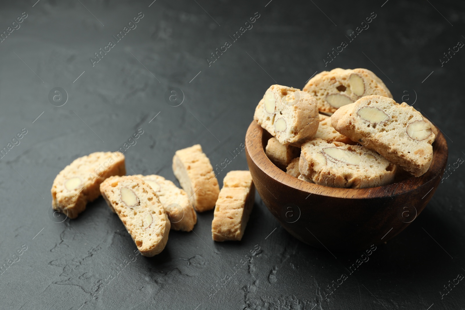 Photo of Traditional Italian almond biscuits (Cantucci) in bowl on black table