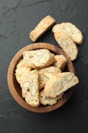 Photo of Traditional Italian almond biscuits (Cantucci) in bowl on black table, top view