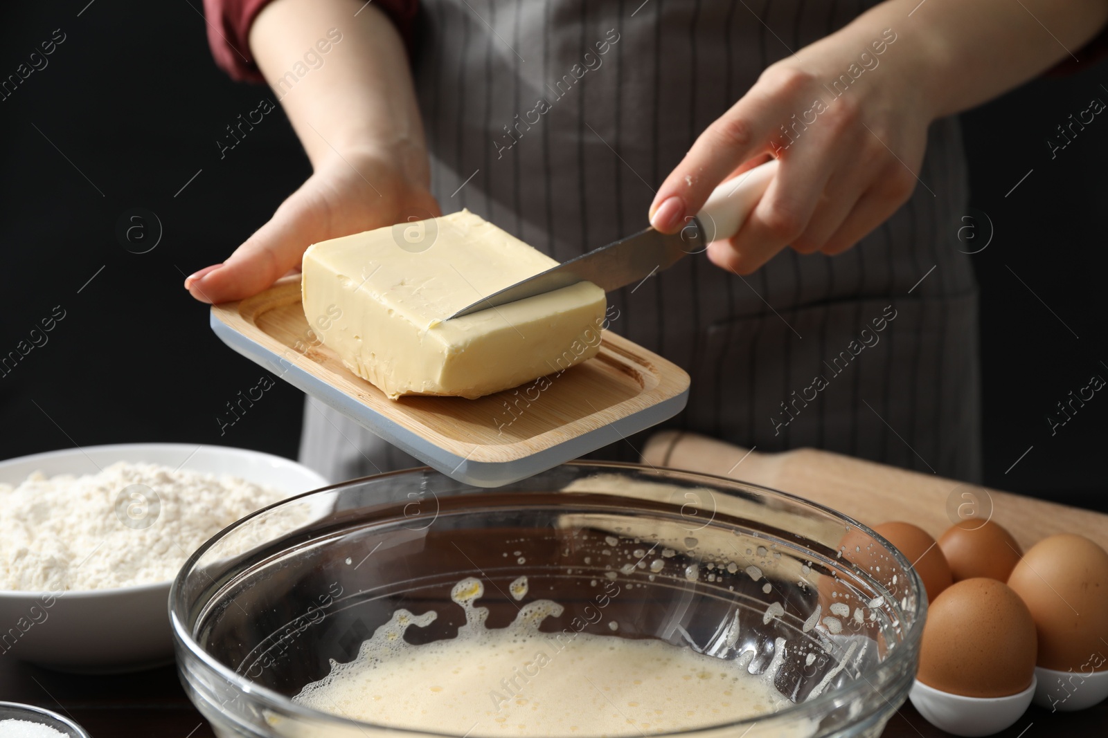 Photo of Making cookies. Woman adding butter into dough at table, closeup