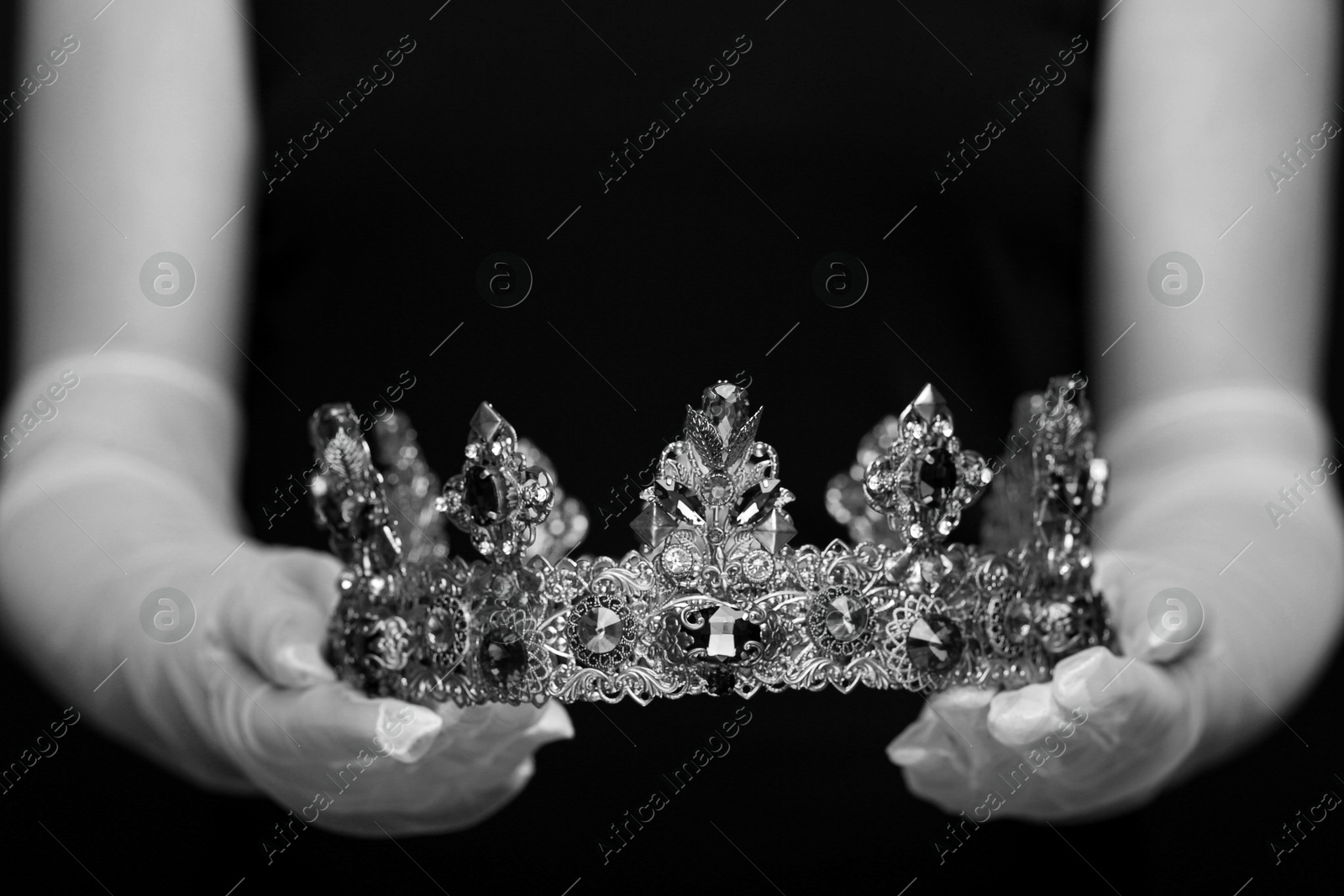 Image of Woman holding luxury crown, closeup. Black-and-white photo