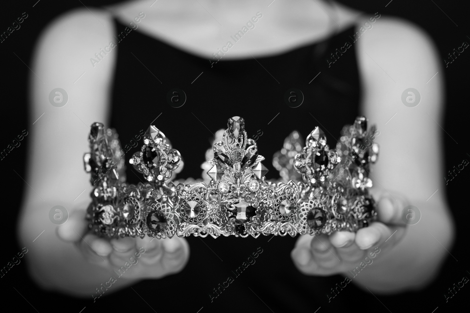 Image of Woman holding luxury crown, closeup. Black-and-white photo