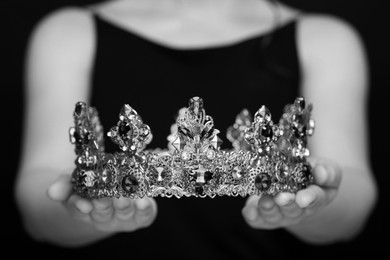 Woman holding luxury crown, closeup. Black-and-white photo