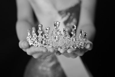 Image of Woman holding luxury crown, closeup. Black-and-white photo