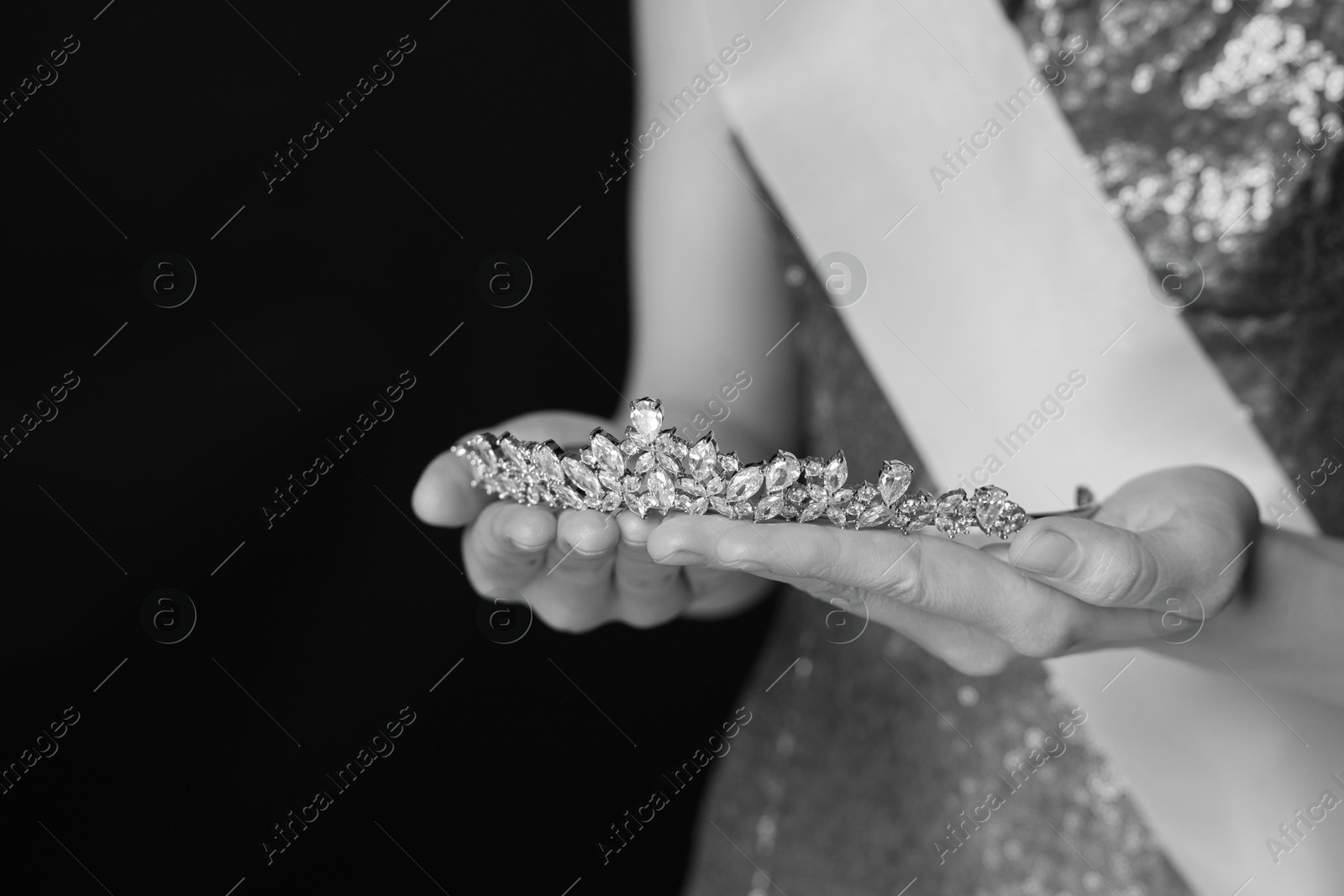 Image of Woman holding luxury tiara, closeup. Black-and-white photo