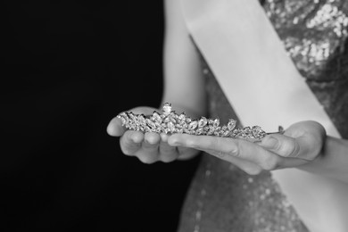 Woman holding luxury tiara, closeup. Black-and-white photo