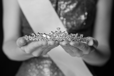 Image of Woman holding luxury tiara, closeup. Black-and-white photo