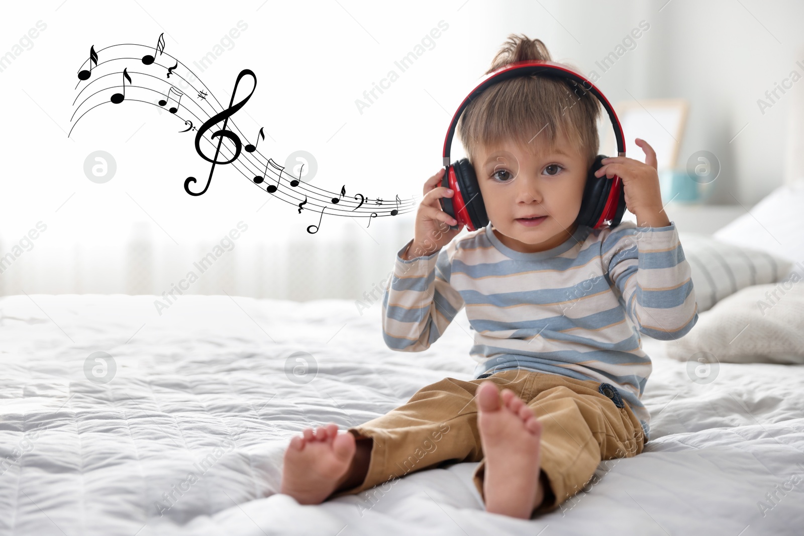 Image of Cute little baby in headphones on bed at home. Music notes flying near child