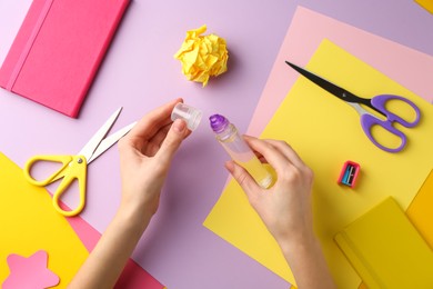 Photo of Woman with glue, scissors and colorful paper at table, top view