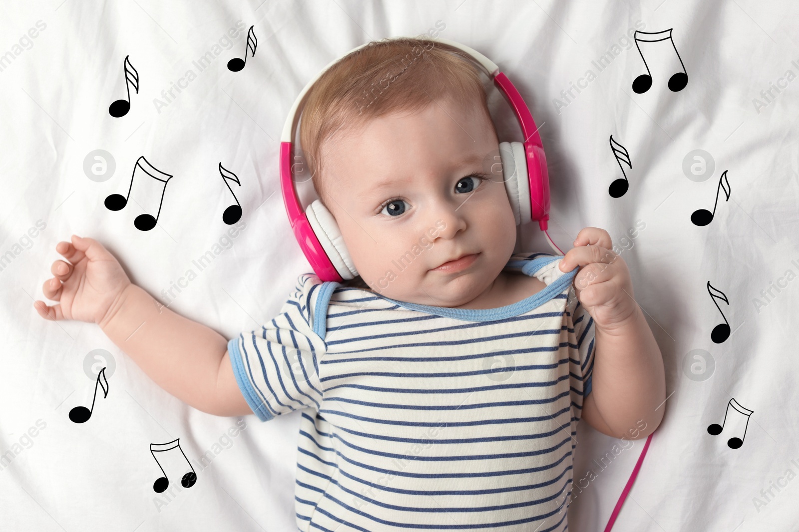 Image of Cute little baby with headphones lying on bed, top view. Music notes flying near child