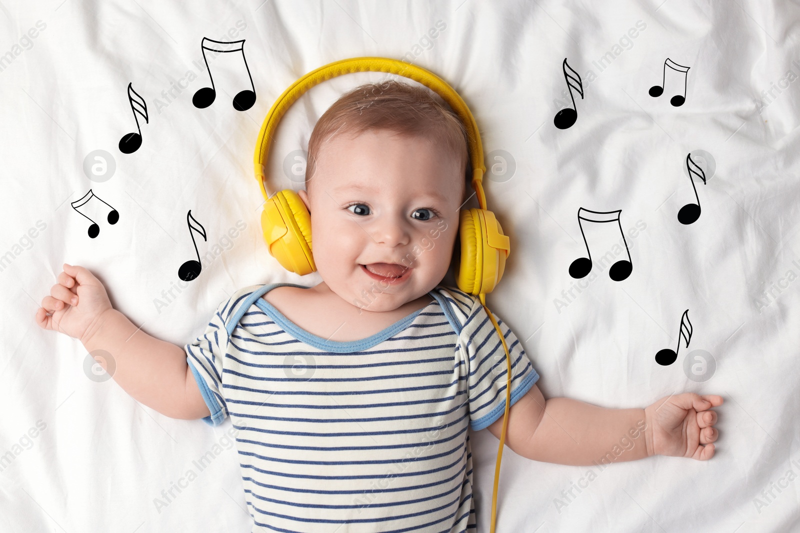 Image of Cute little baby with headphones lying on bed, top view. Music notes flying near child