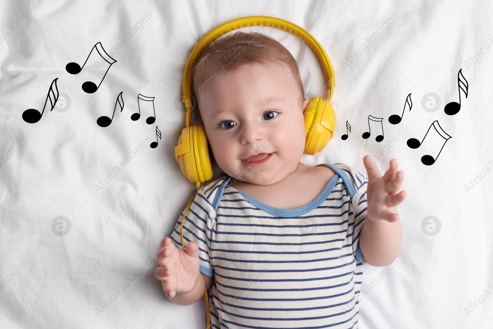 Image of Cute little baby with headphones lying on bed, top view. Music notes flying near child