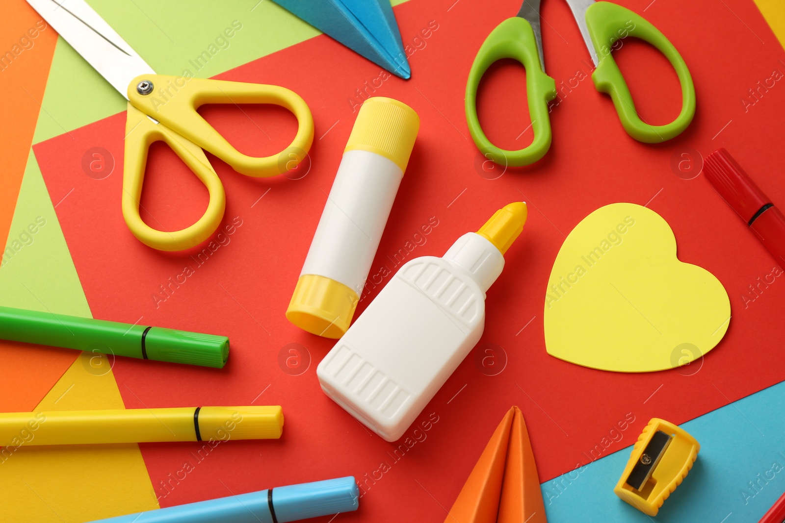 Photo of Glue, scissors and other stationery on color background, above view