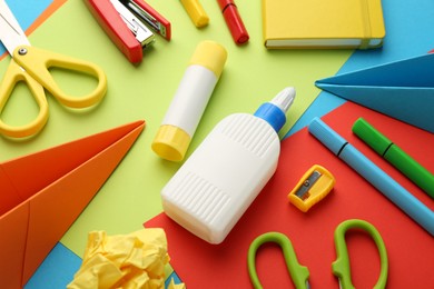 Photo of Glue, scissors and other stationery on color background, above view