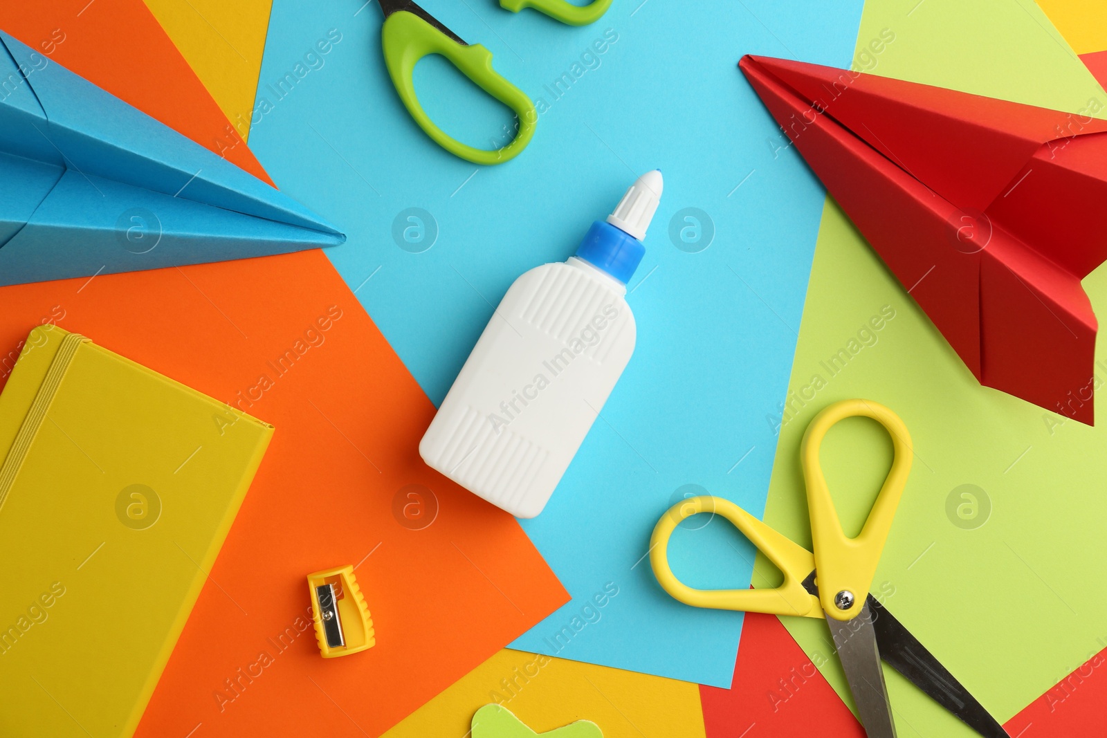 Photo of Flat lay composition with glue, scissors and other stationery on color background