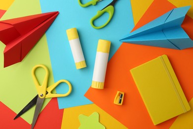 Flat lay composition with glue, scissors and other stationery on color background