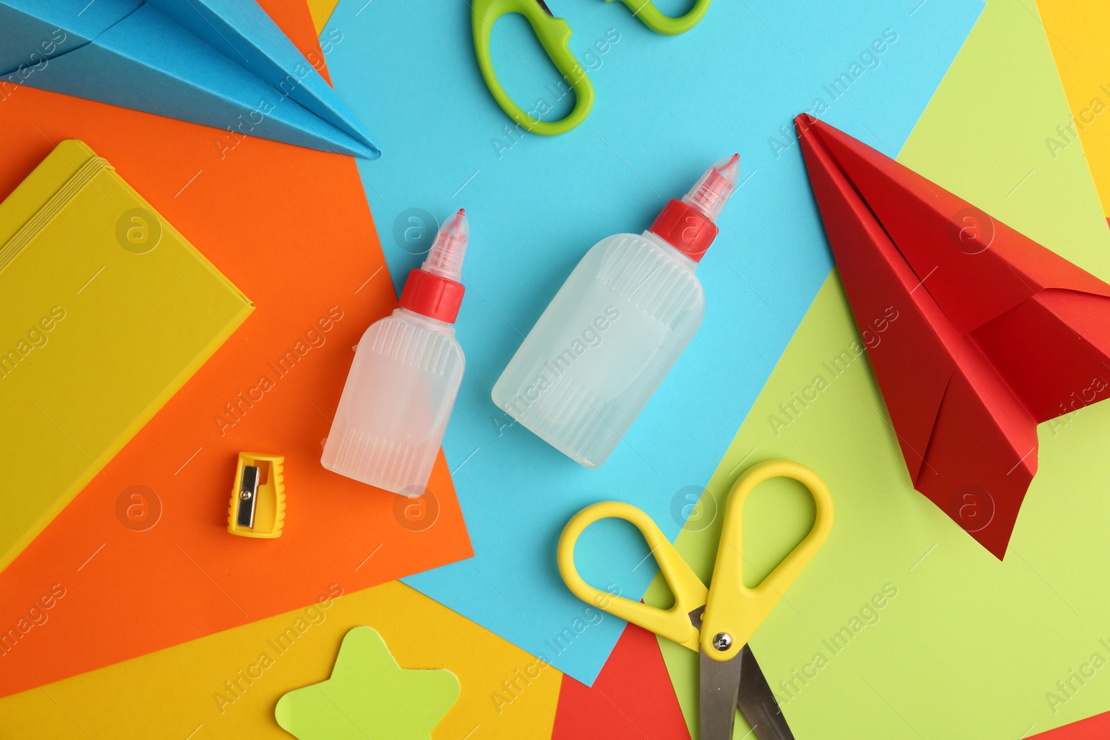 Photo of Flat lay composition with glue, scissors and other stationery on color background