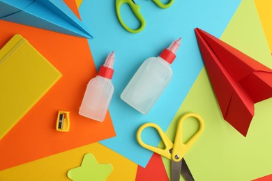 Photo of Flat lay composition with glue, scissors and other stationery on color background