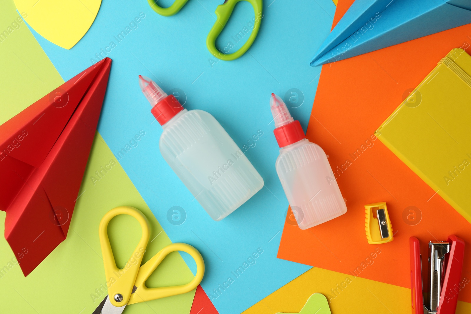 Photo of Flat lay composition with glue, scissors and other stationery on color background