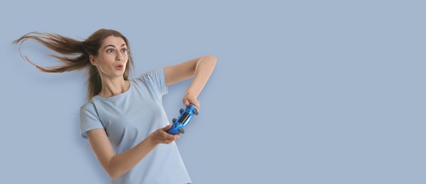 Excited woman playing video games with controller on light blue background. Banner design with space for text