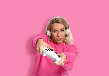 Image of Woman playing video games with controller on pink background