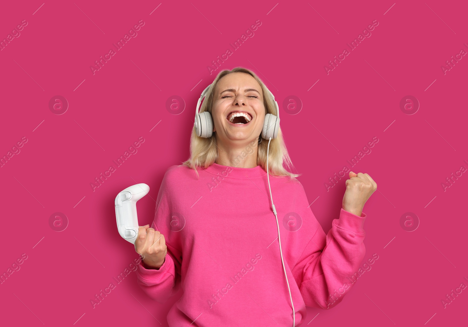 Image of Happy woman with controller on pink background