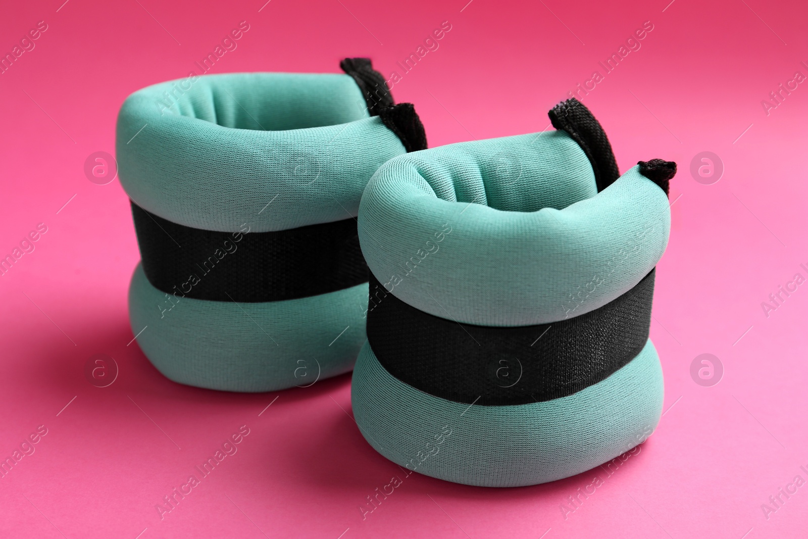 Photo of Stylish turquoise ankle weights on pink background