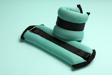 Stylish turquoise ankle weights on color background