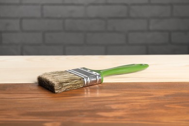 Photo of Applying walnut wood stain. Brush on wooden surface, closeup