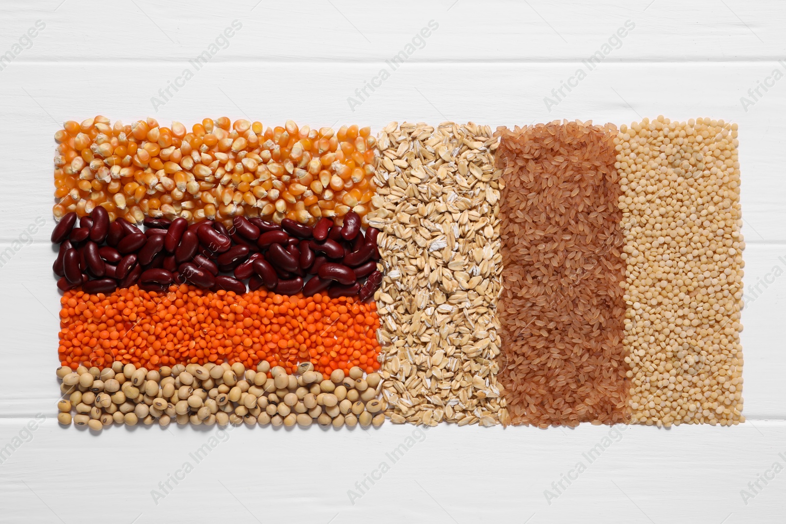 Photo of Different types of cereals and legumes on white wooden table, top view