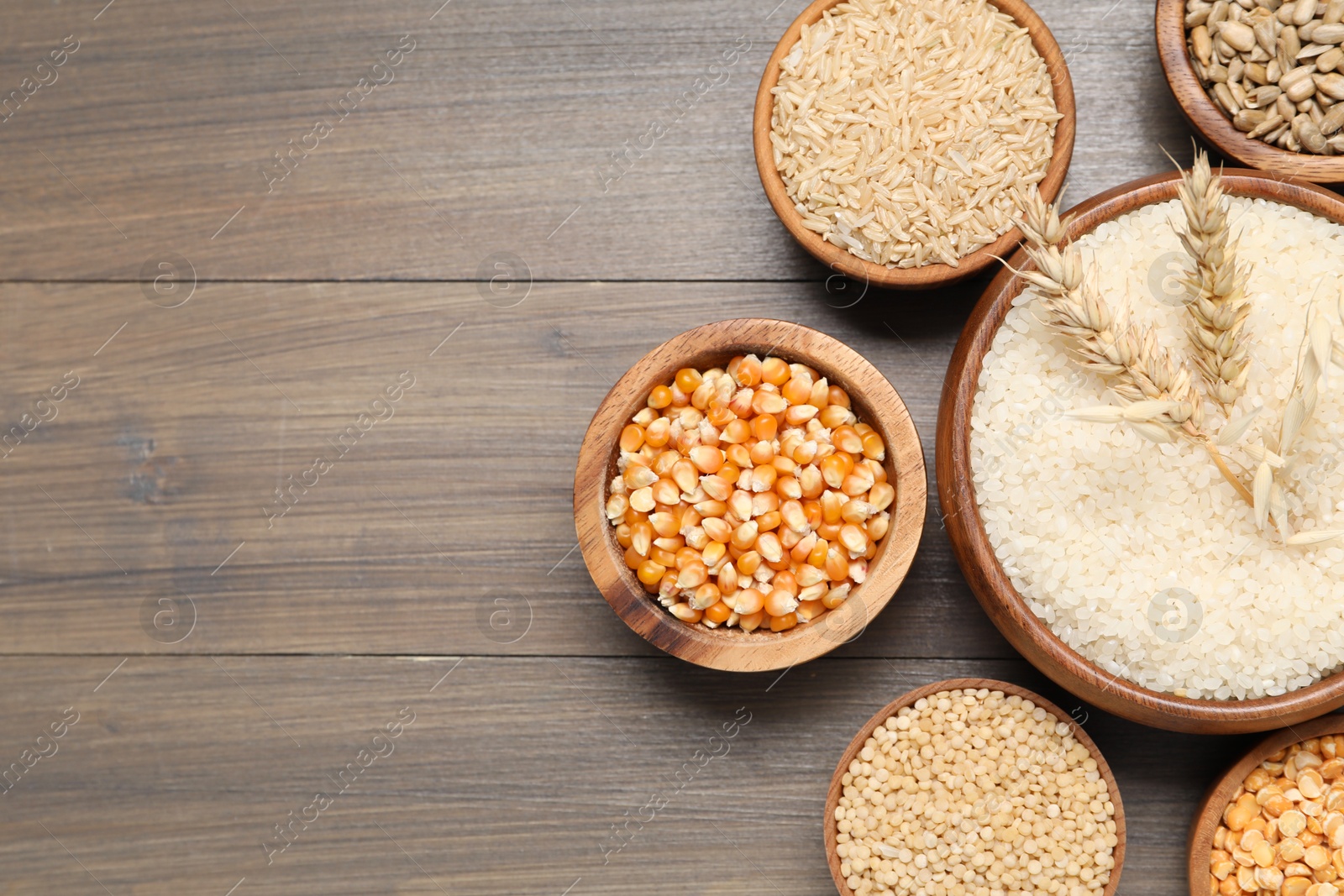 Photo of Different types of cereals and seeds on wooden table, flat lay. Space for text