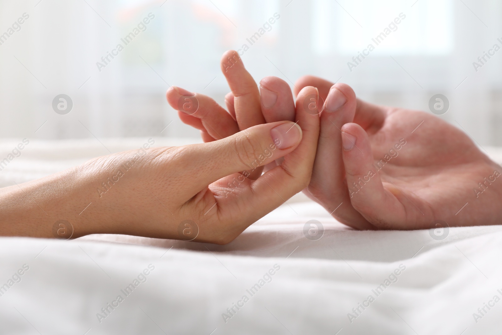 Photo of Lovely couple holding hands in bed, closeup