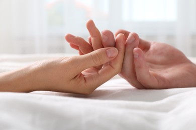 Photo of Lovely couple holding hands in bed, closeup