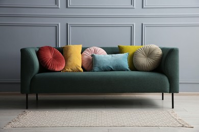 Photo of Stylish sofa with cushions near grey wall