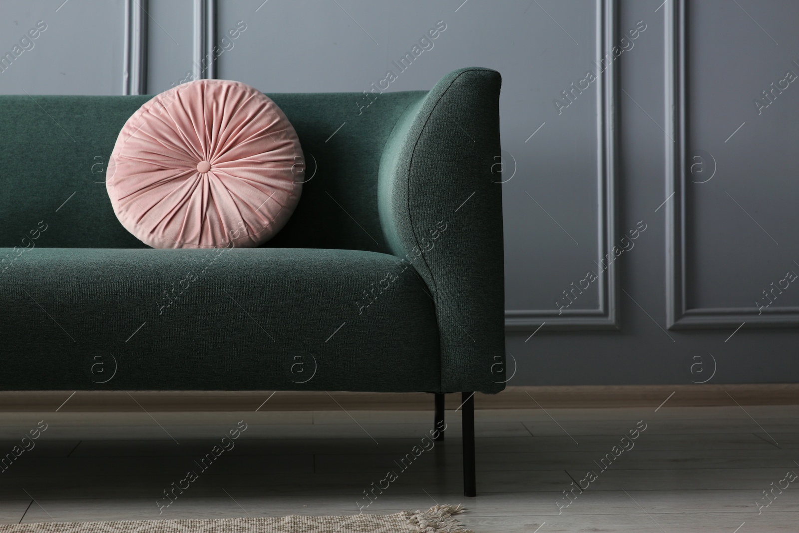 Photo of Stylish sofa with cushion near grey wall