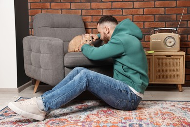 Photo of Man petting cute ginger cat at home