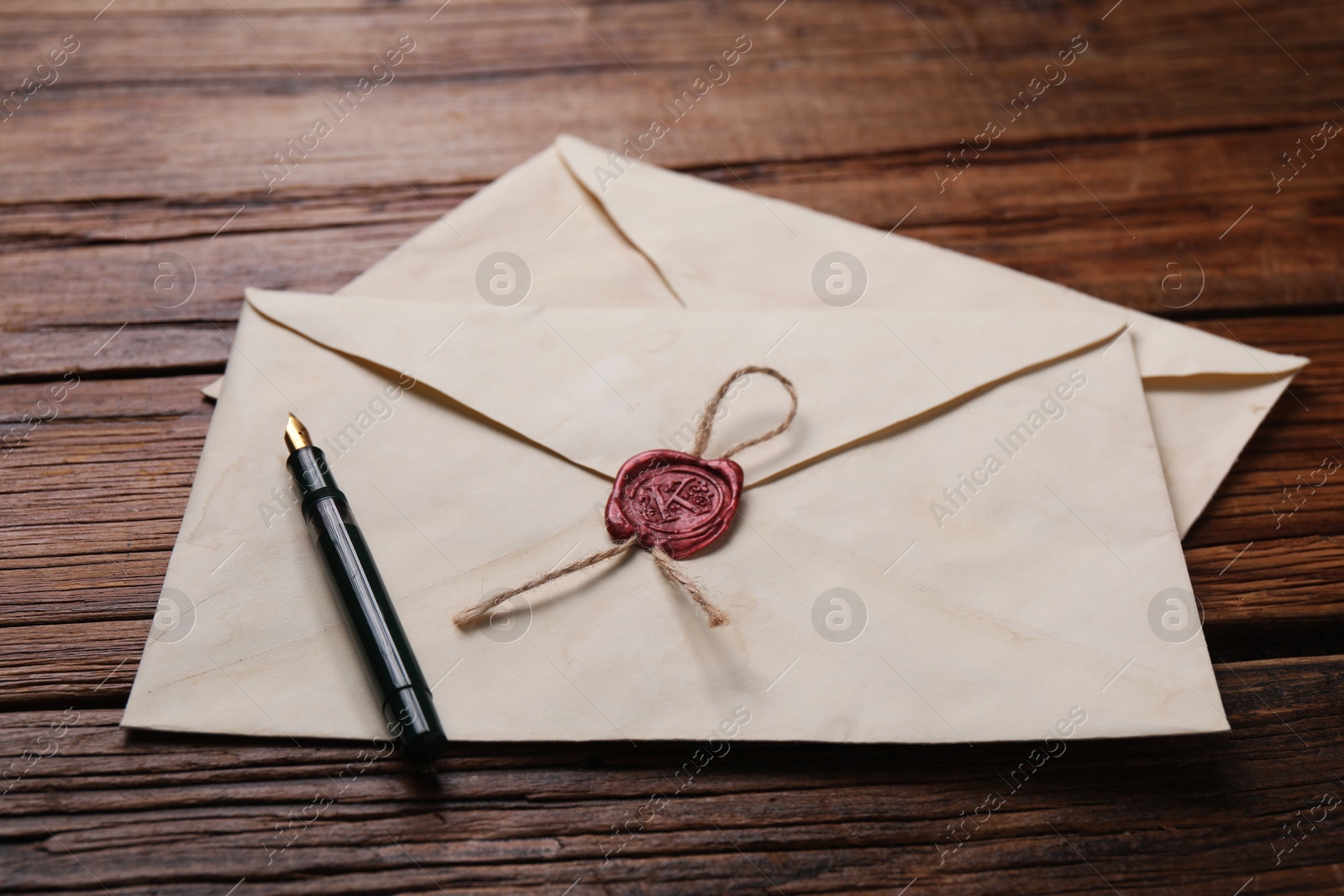 Photo of Old letter envelopes and pen on wooden table, closeup