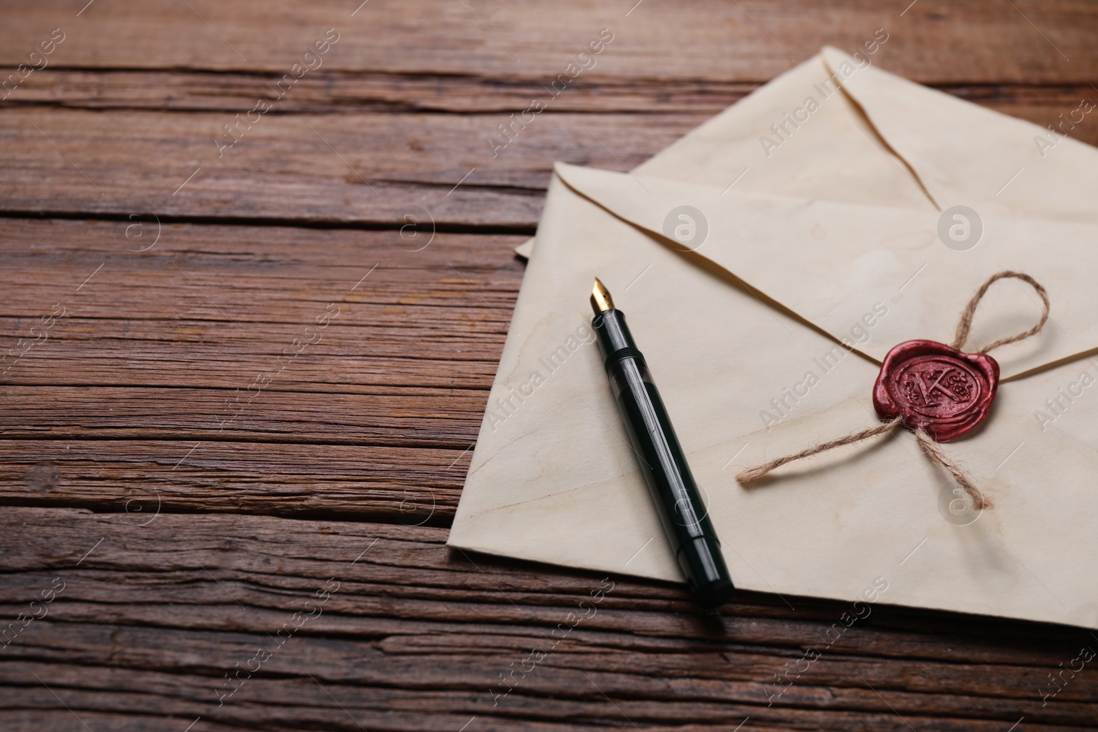 Photo of Old letter envelopes and pen on wooden table, closeup