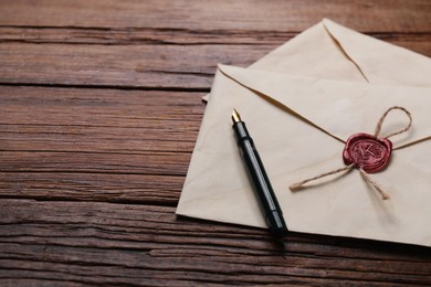 Old letter envelopes and pen on wooden table, closeup