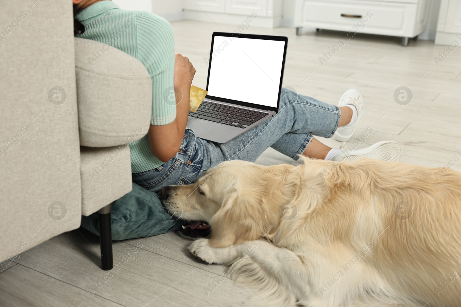 Photo of Online pet shop. Woman with laptop, credit card and cute Golden Retriever dog making order on floor at home, closeup