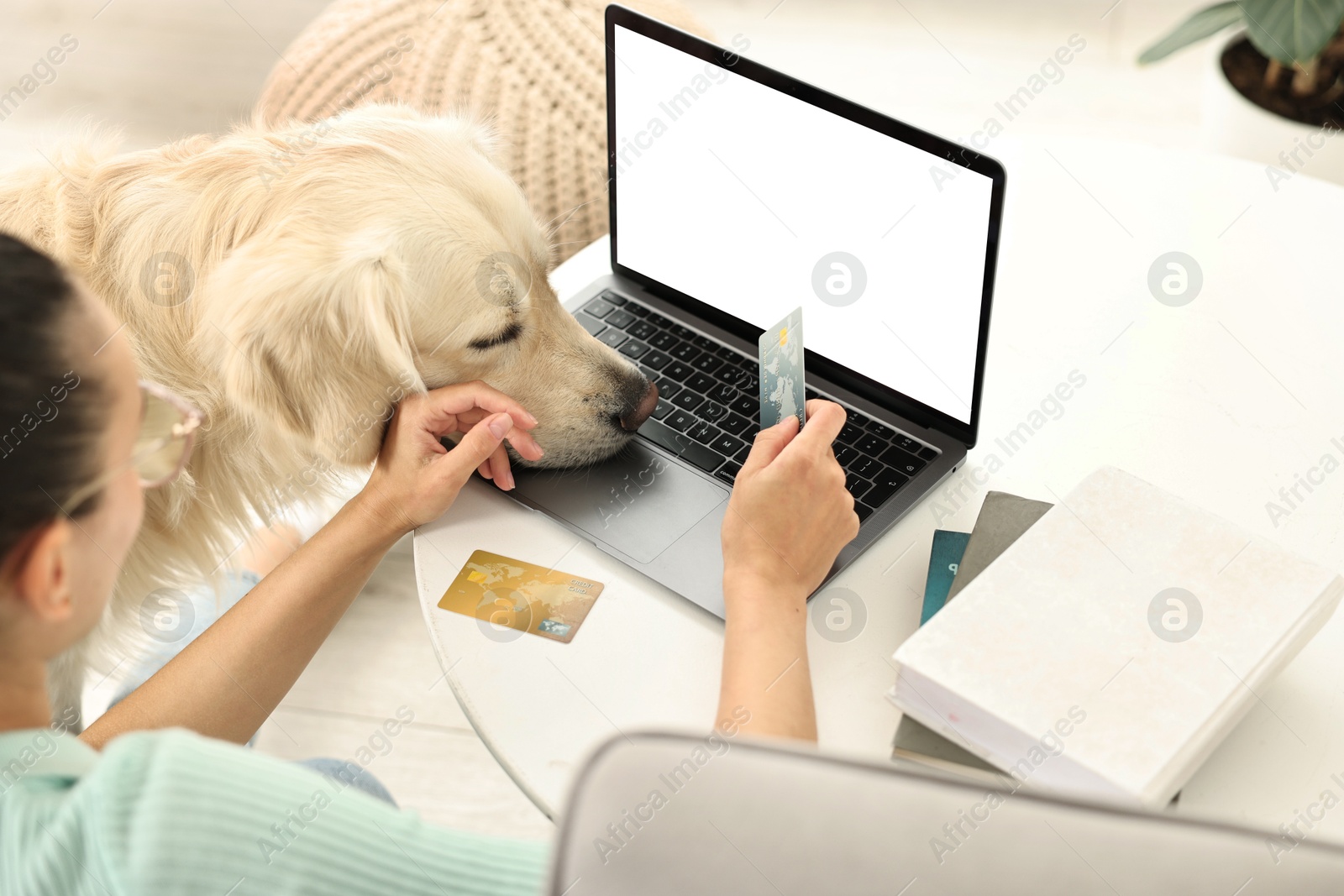 Photo of Online pet shop. Woman with laptop, credit card and cute Golden Retriever dog making order at home, closeup