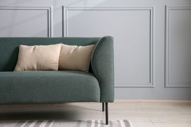 Photo of Comfortable sofa near grey wall in room, space for text