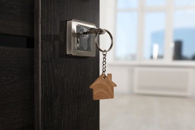 Photo of Open door with key and house shaped keychain, closeup. Space for text