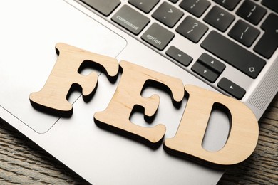 Photo of Letters Fed (Federal Reserve System) and laptop on wooden table, closeup