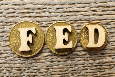 Photo of Letters Fed (Federal Reserve System) and coins on wooden table, flat lay