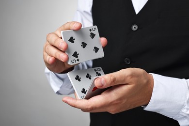 Professional croupier shuffling cards on grey background